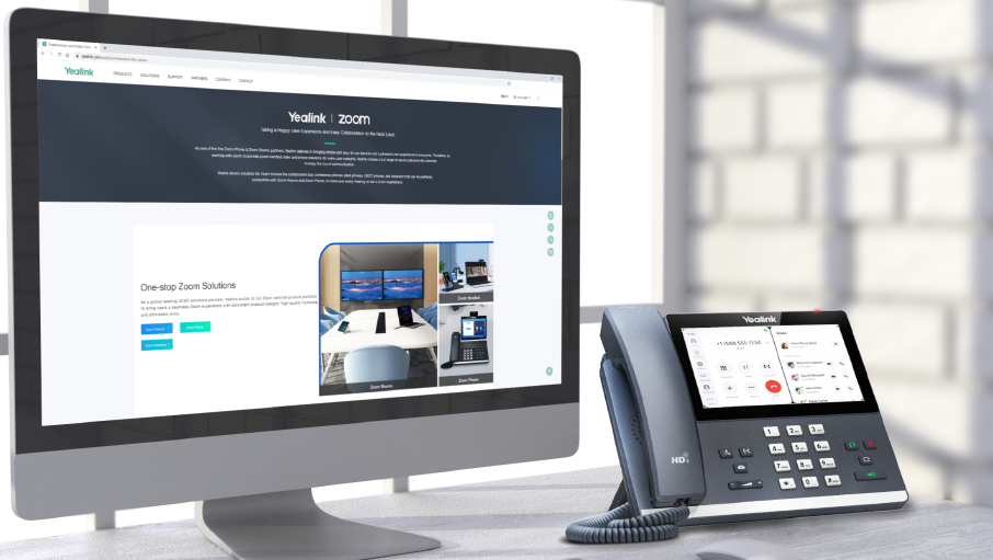 Yealink desk phone beside a computer monitor