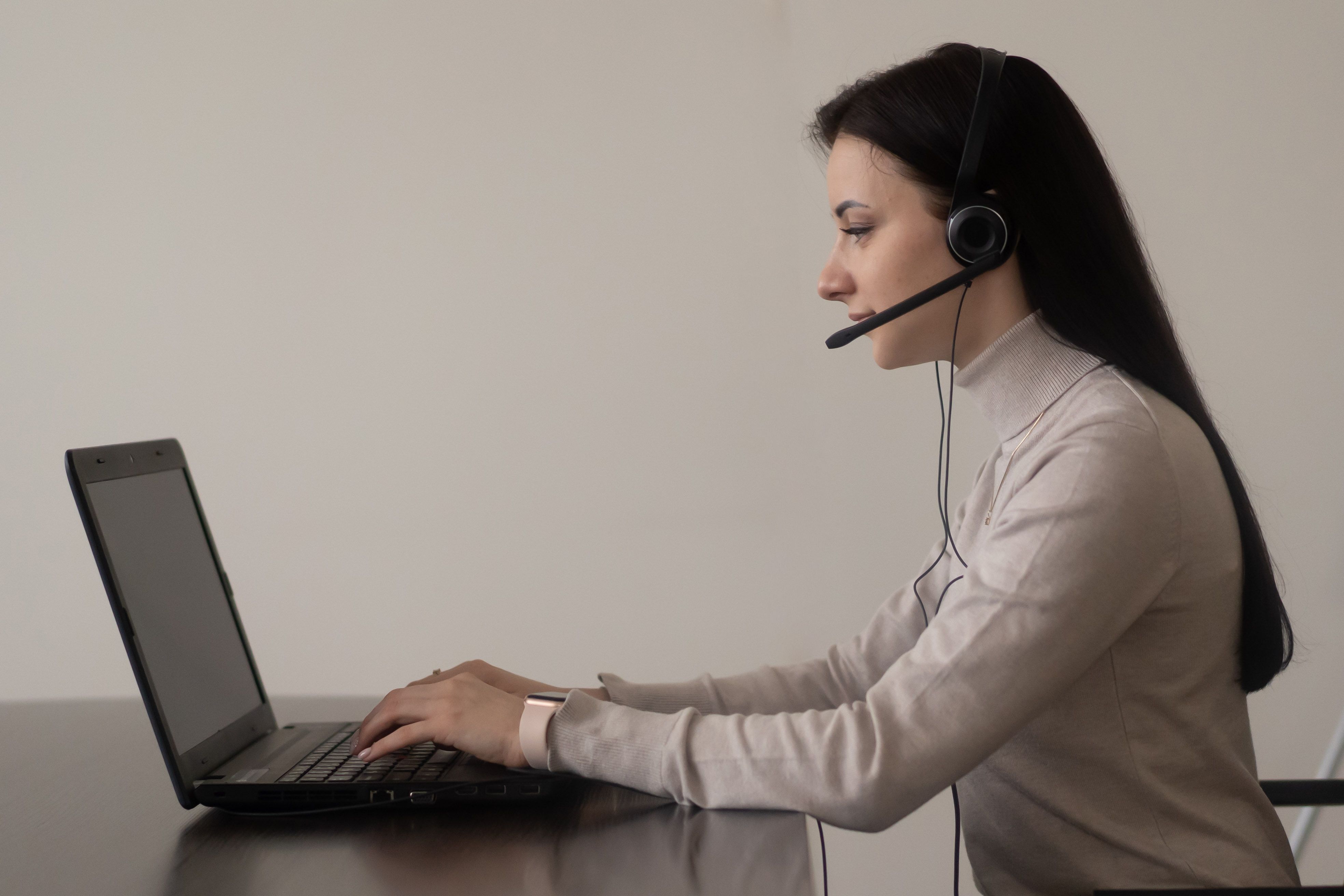 Woman wearing a Bluetooth headset working at a laptop