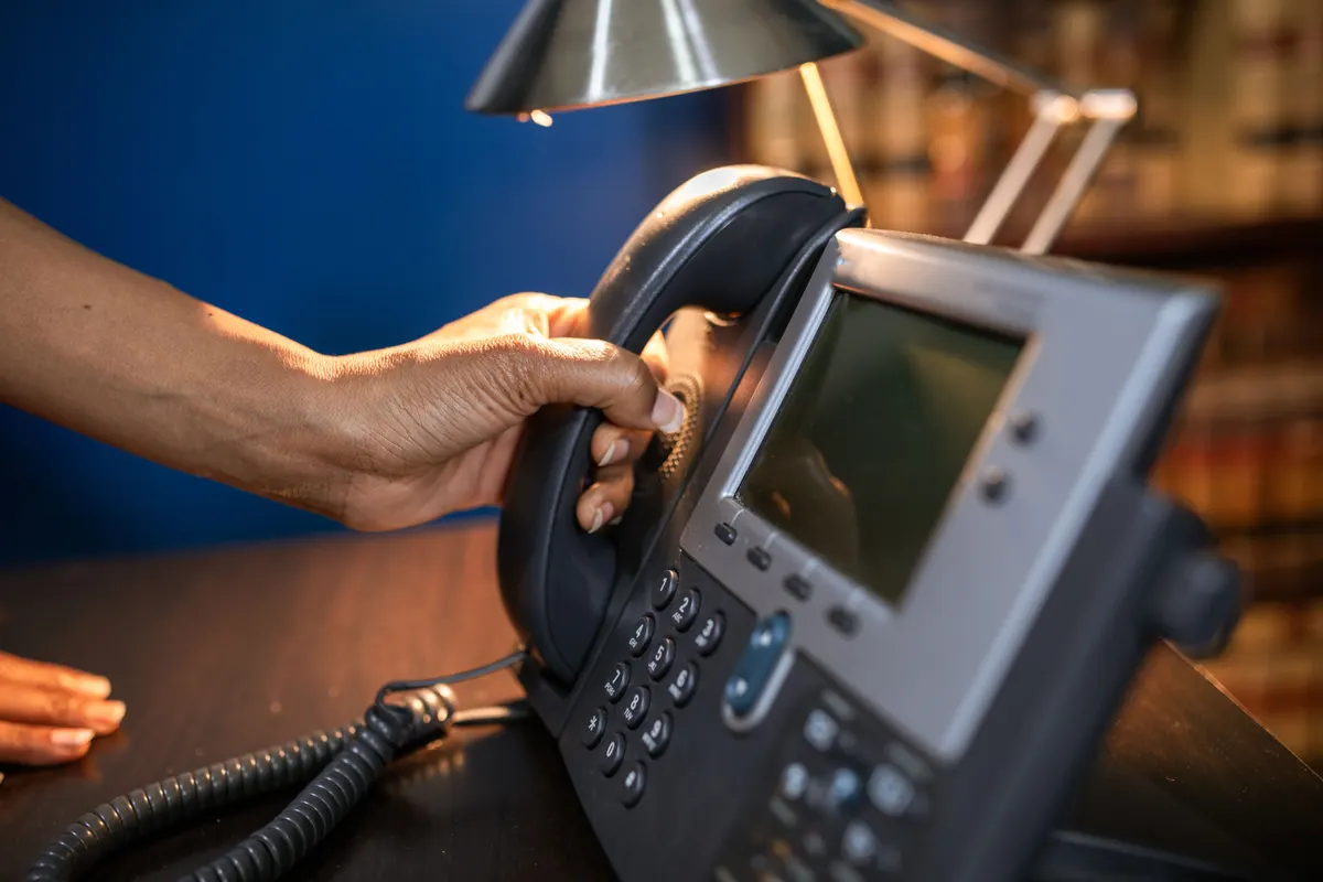 Man smiling on a phone call while using his laptop