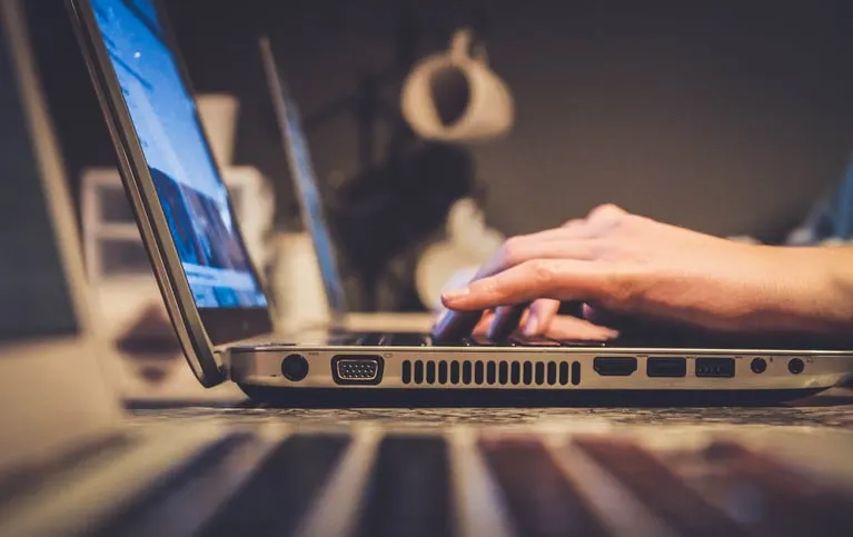 Side view of hands typing on a laptop showing its side ports