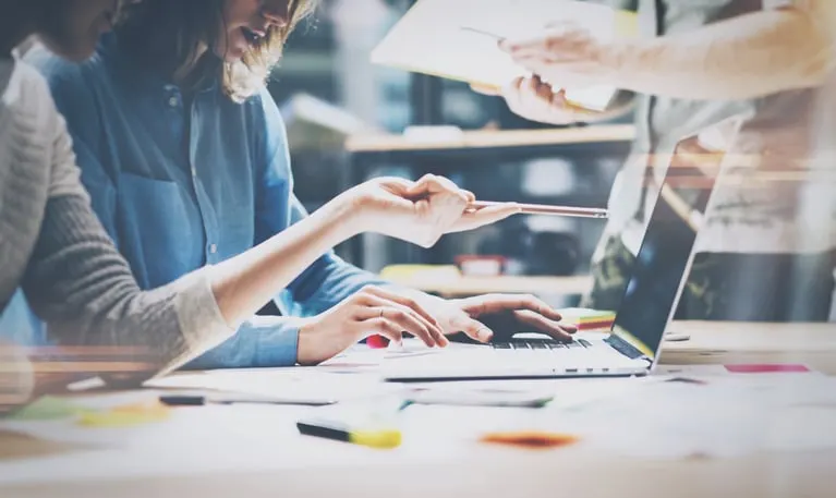 Colleagues pointing at a laptop screen during a meeting